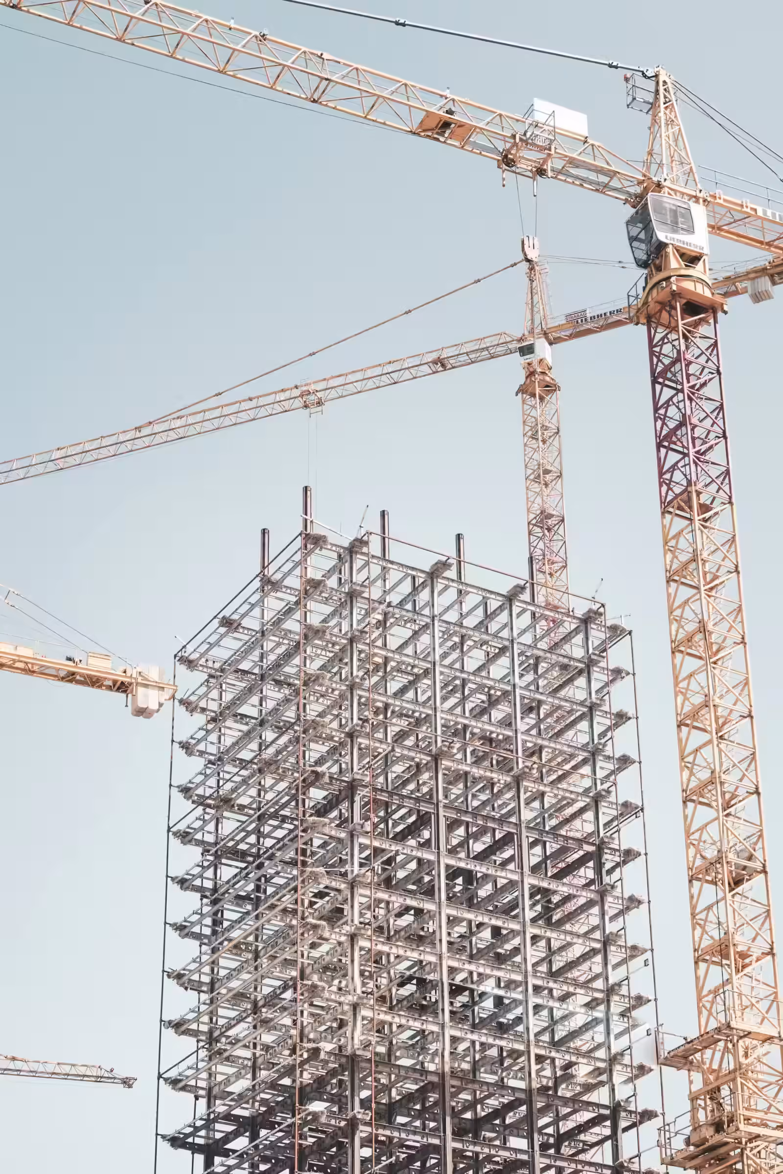 Structure mÃ©tallique grise d'un bÃ¢timent prÃ¨s d'une grue Ã  tour pendant la journÃ©e